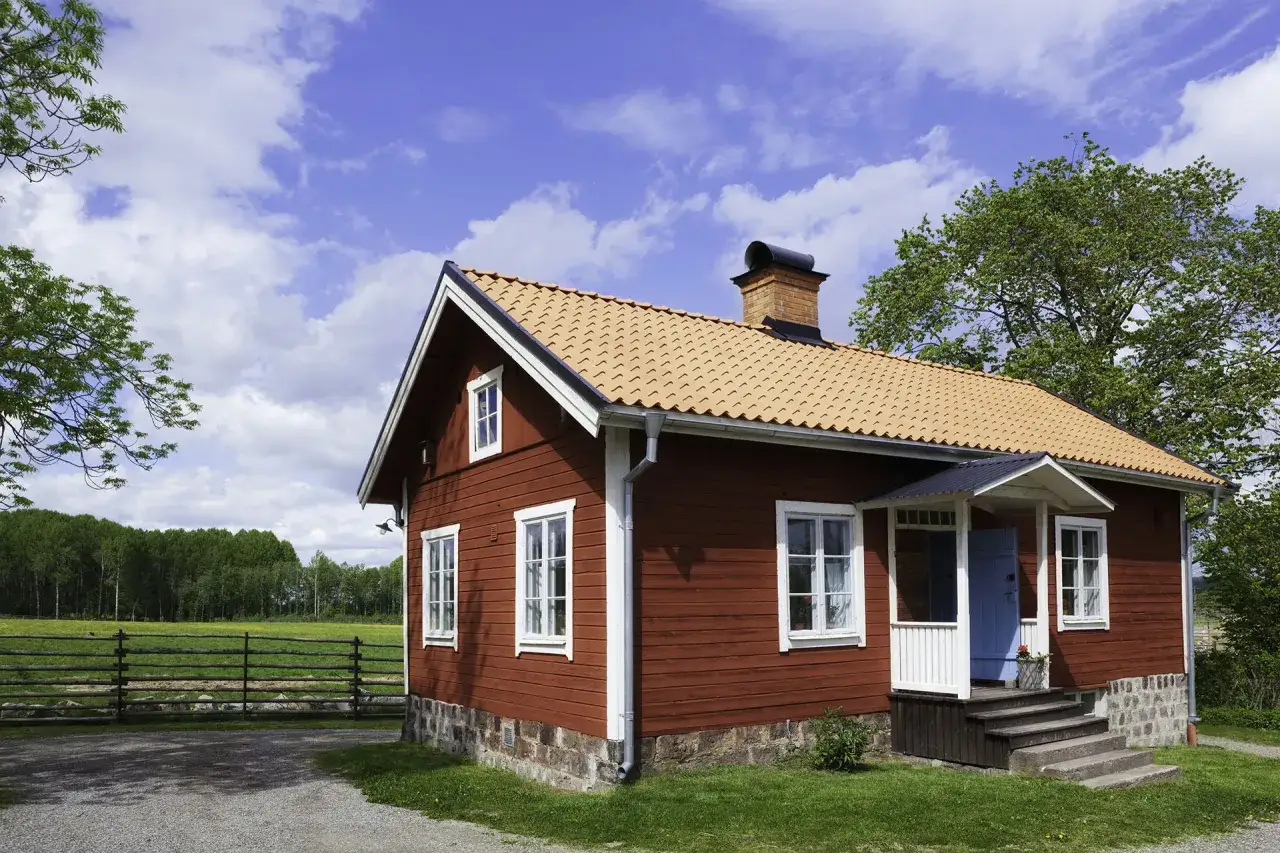 R&ouml;tt hus med tegeltak och en vacker gavel.