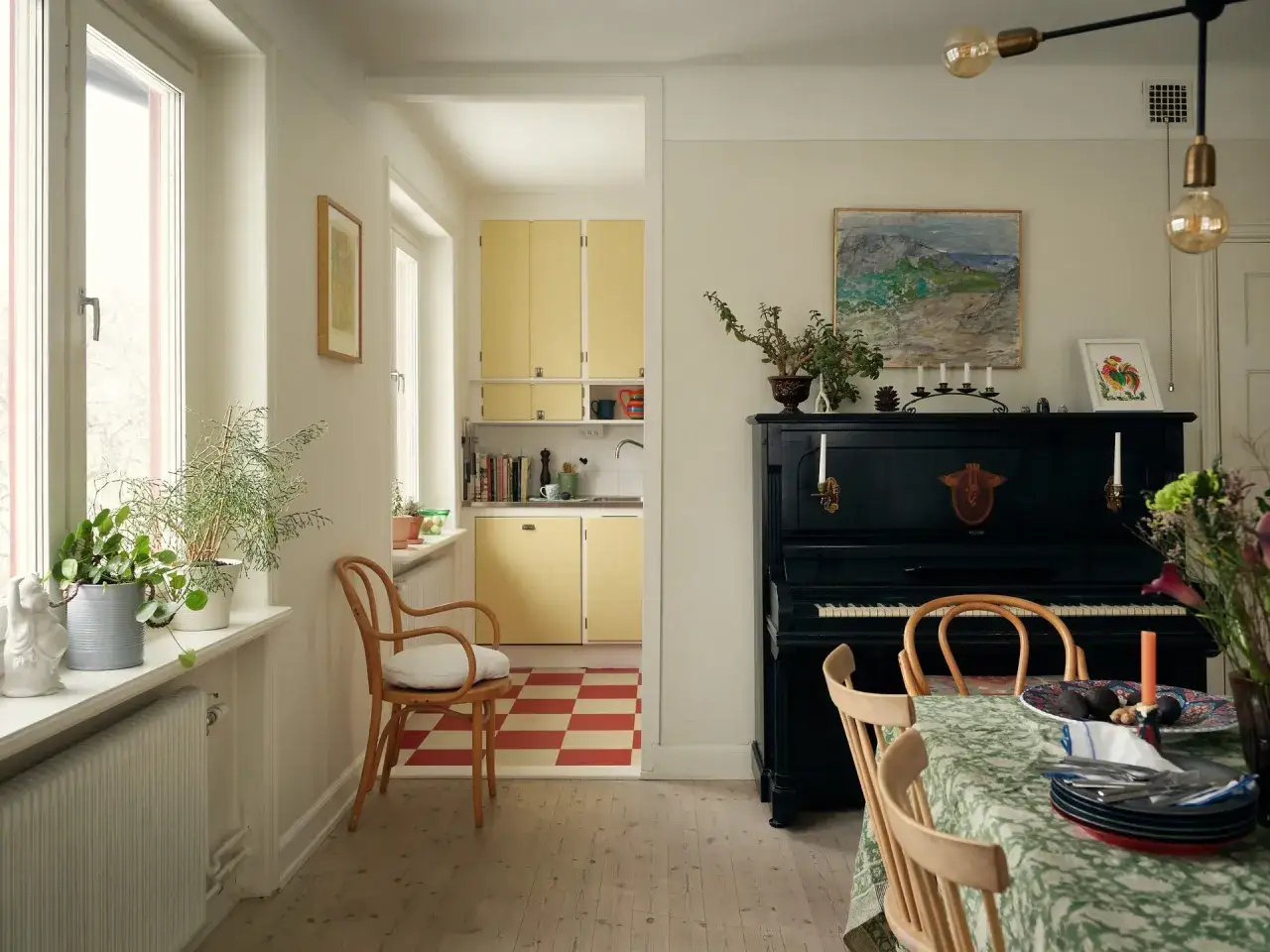 Vardagsrum med pianot, matbord och k&ouml;k i ett tidstypiskt 30-talshus.